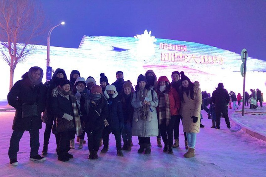 A group of people standing on a snow-covered ground with a large illuminated sign in the background. 4