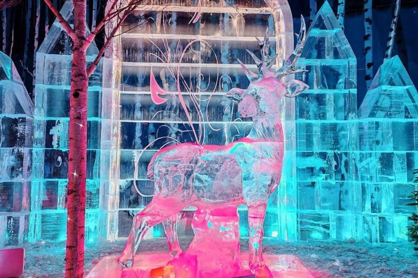 An ice sculpture of a deer in front of a transparent ice house. 1