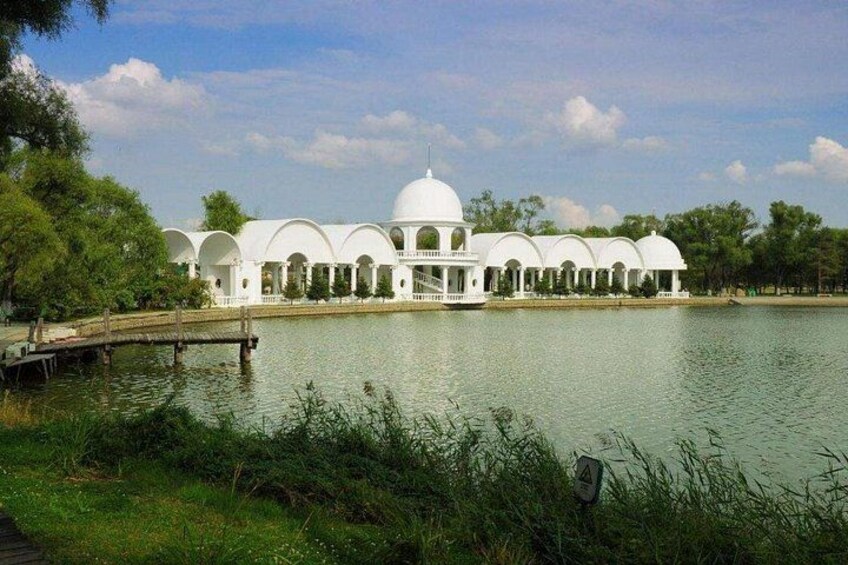 Un edificio bianco con cupole, un lago e un ponte di legno. 2