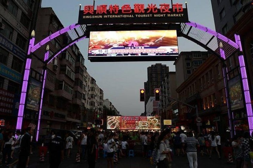 A busy street with illuminated signs and a large digital billboard at an intersection. 4
