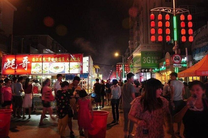 A busy street at night with illuminated signs and a crowd of people. 5
