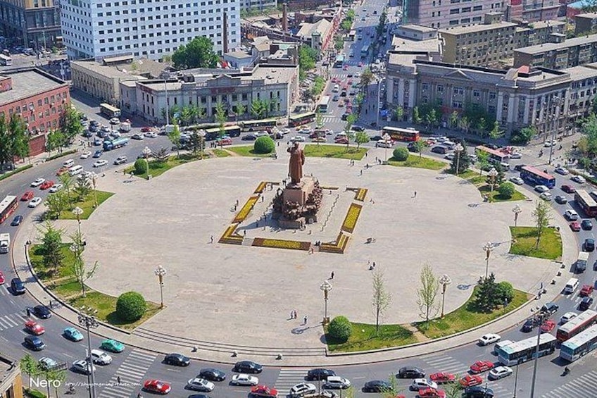 A roundabout with a central monument surrounded by greenery and buildings. 3