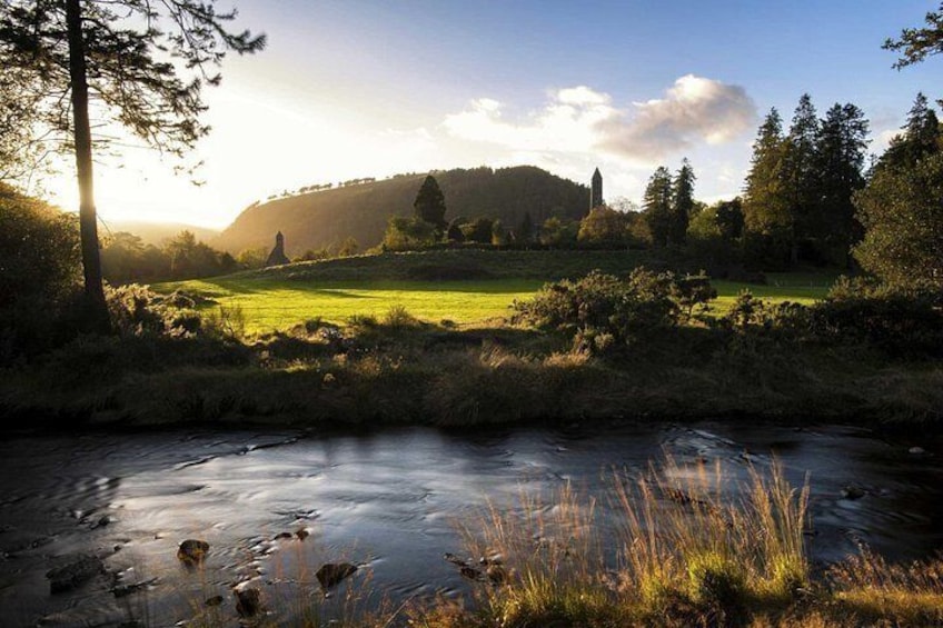 Un río, campos cubiertos de hierba, árboles y una colina distante con una estructura. 3