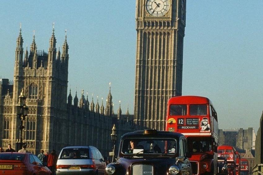 Una strada trafficata con un autobus a due piani, una torre dell'orologio e architettura gotica. 4