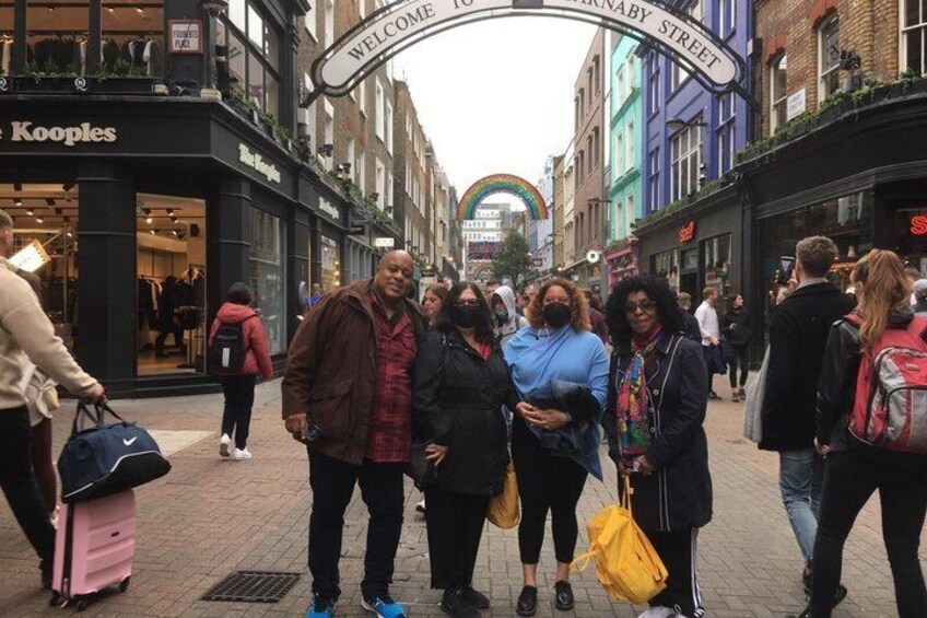 A group of people standing on a pedestrian street with shops on either side. 4
