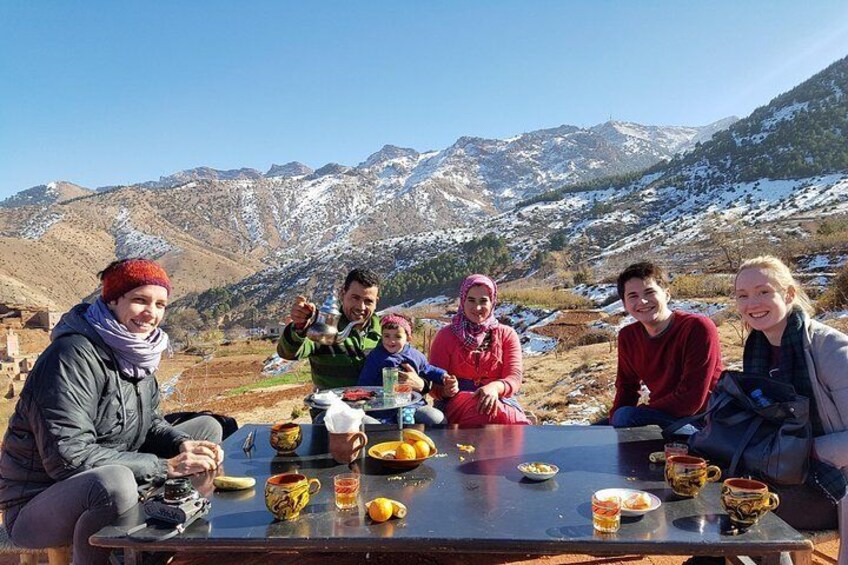 A group of people sitting at a table outdoors with a mountainous landscape in the background. 5