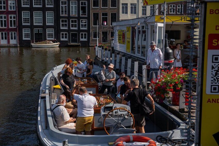 Un barco con pasajeros amarrado cerca de un canal, con edificios al fondo. 5