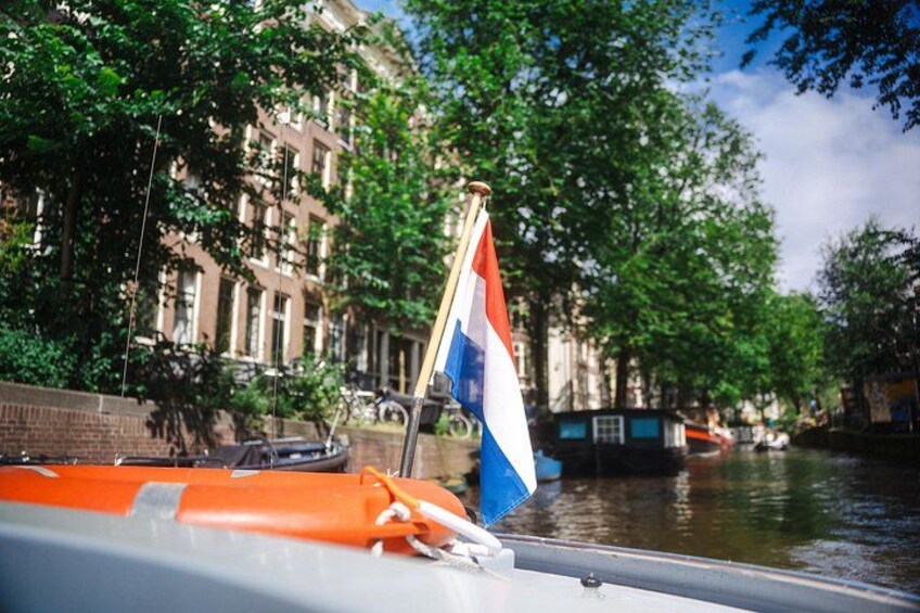 Un canal con un bote, una bandera y edificios a lo largo del agua. 3