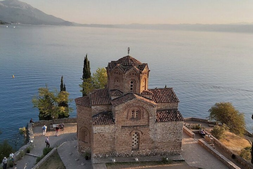 A historic church with a bell tower by a calm lake. 1