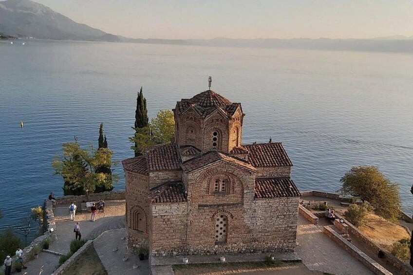 Une église en pierre dotée d’un clocher, située au bord d’un lac. 1