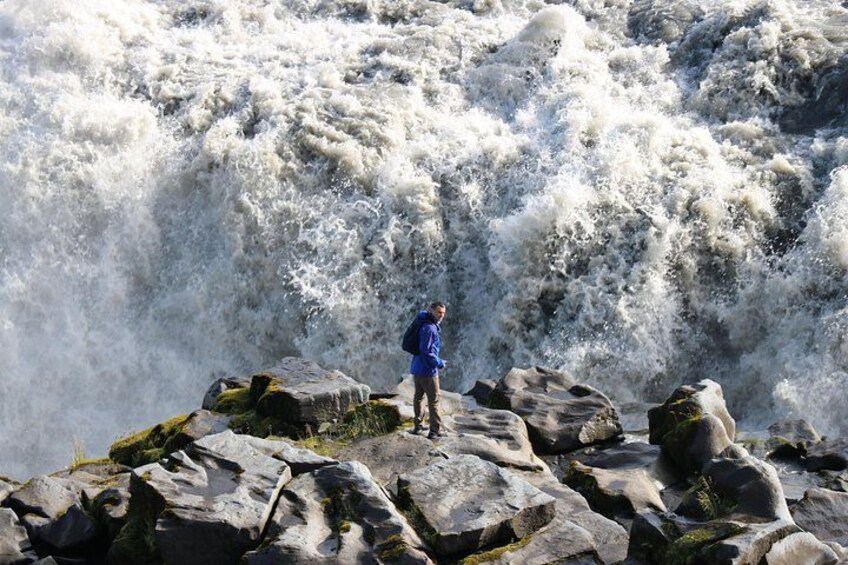 A person standing on rocks by a turbulent river. 2