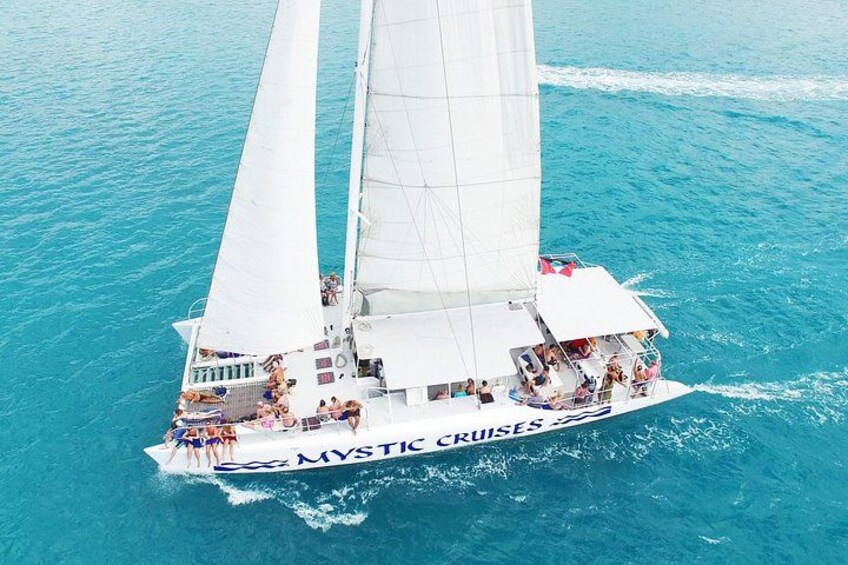 En sejlbåd med navnet 'MYSTIC CRUISES' og flere passagerer, der nyder havet. 2