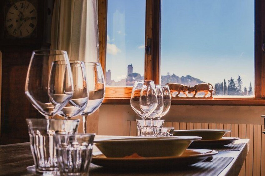 Une table à manger avec des verres à vin et un saladier, une horloge au mur et une vue sur les montagnes par la fenêtre. 5