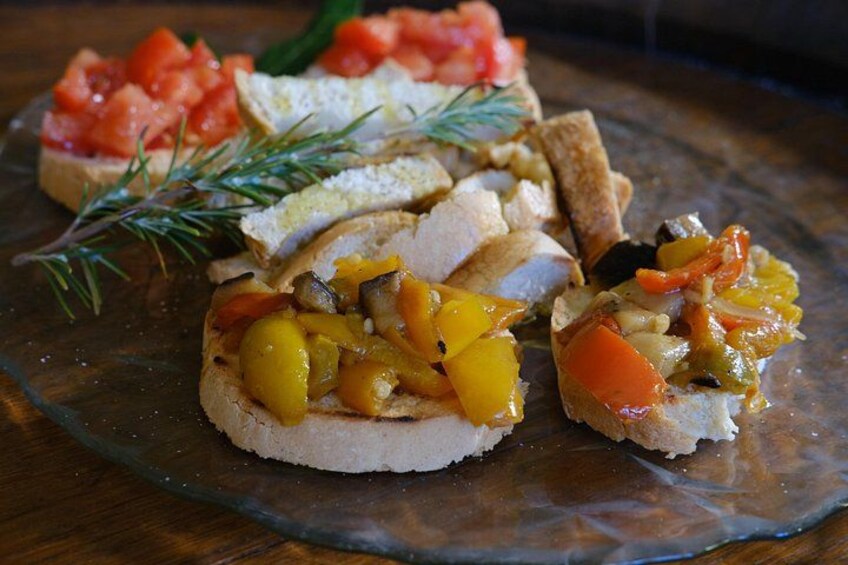 Une assiette en verre contenant divers aliments, notamment du pain garni et une branche de romarin. 2