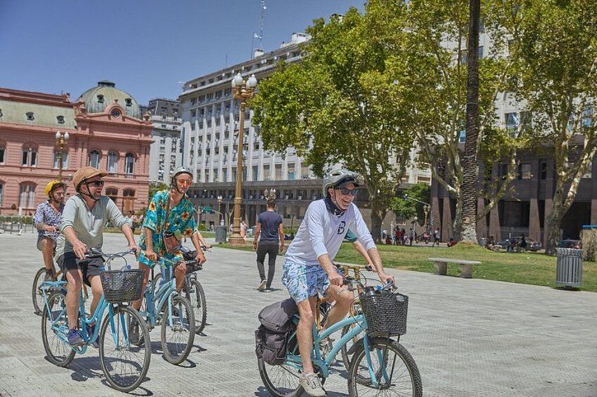 Människor som cyklar på ett torg i en stad, med byggnader och träd i bakgrunden. 4