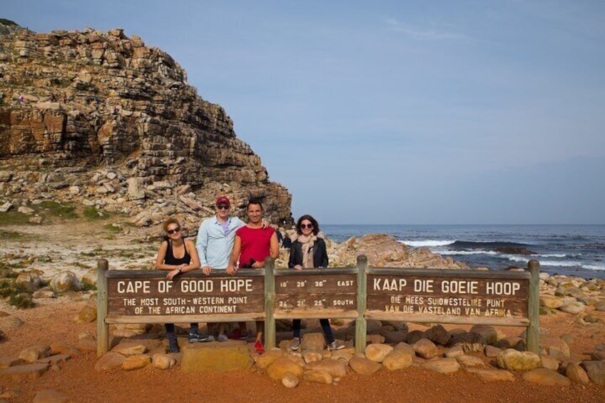 En grupp människor står framför en skylt med texten ”Cape of Good Hope” och ”Kaap Die Goeie Hoop”. 4