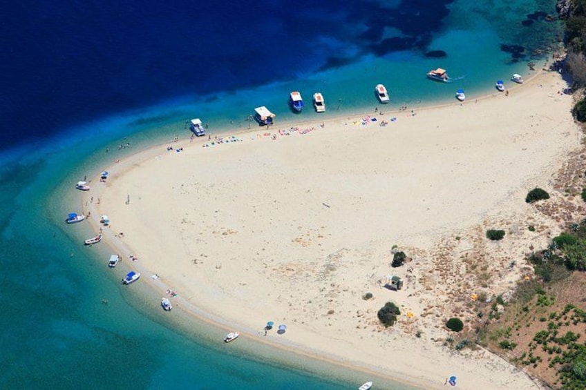 Vista aérea de una playa con barcos, sombrillas y gente. 2