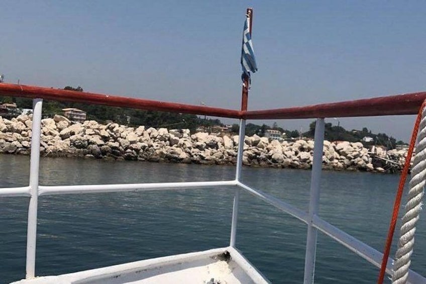 Barandilla de barco, agua tranquila y una costa rocosa con una bandera. 5