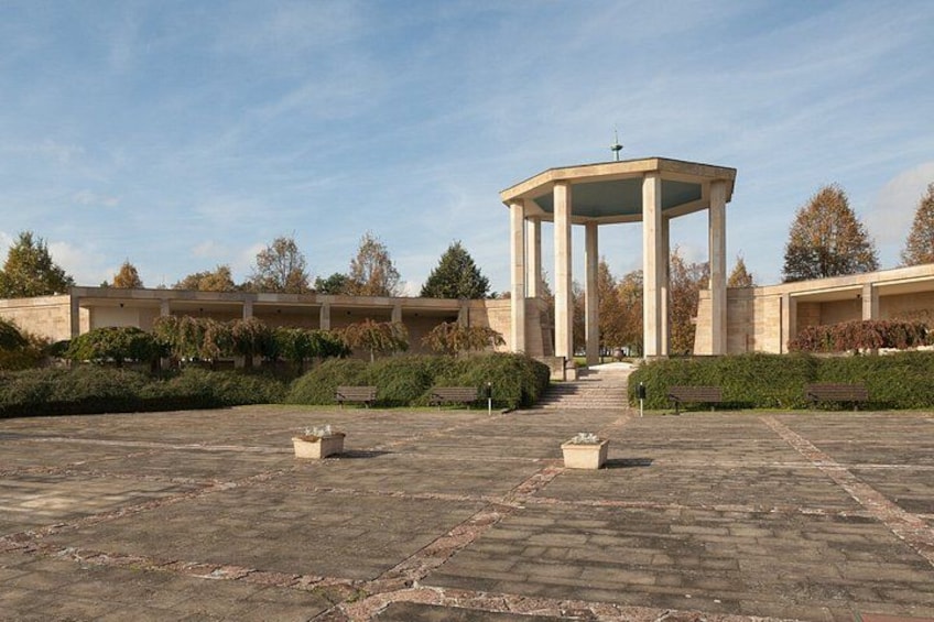 A gazebo with a dome roof, surrounded by a garden with benches and trees. 5