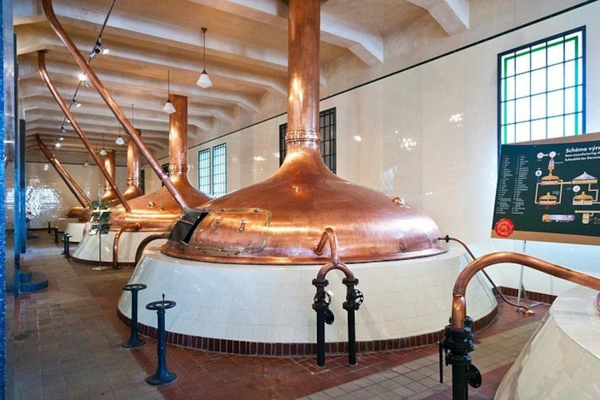 A large copper distillation apparatus in a museum setting with informational displays. 4