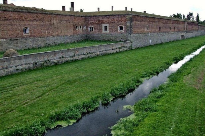 Een bakstenen gebouw met een grasveld en een smalle waterloop. 2