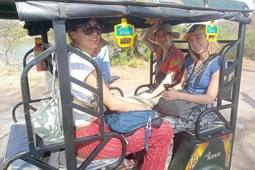 A group of people in a safari vehicle with a canopy, surrounded by natural scenery. 4