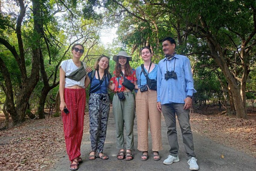 Un grupo de personas de pie en una zona boscosa con árboles y un sendero. 1