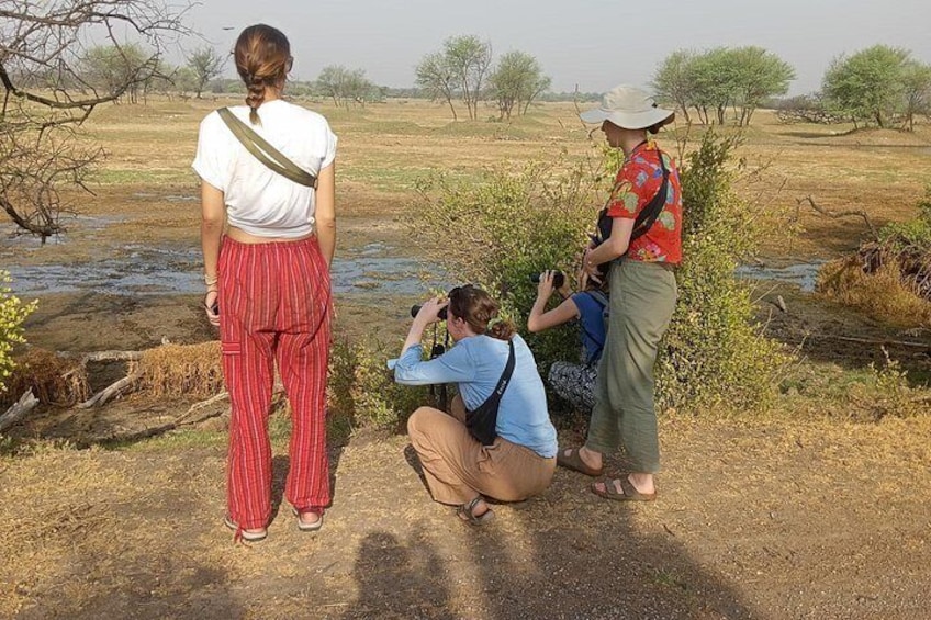 Three people in an outdoor setting with a body of water and sparse vegetation. 2