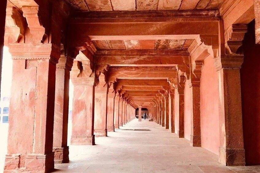 A corridor with red stone columns and a long, straight pathway. 5