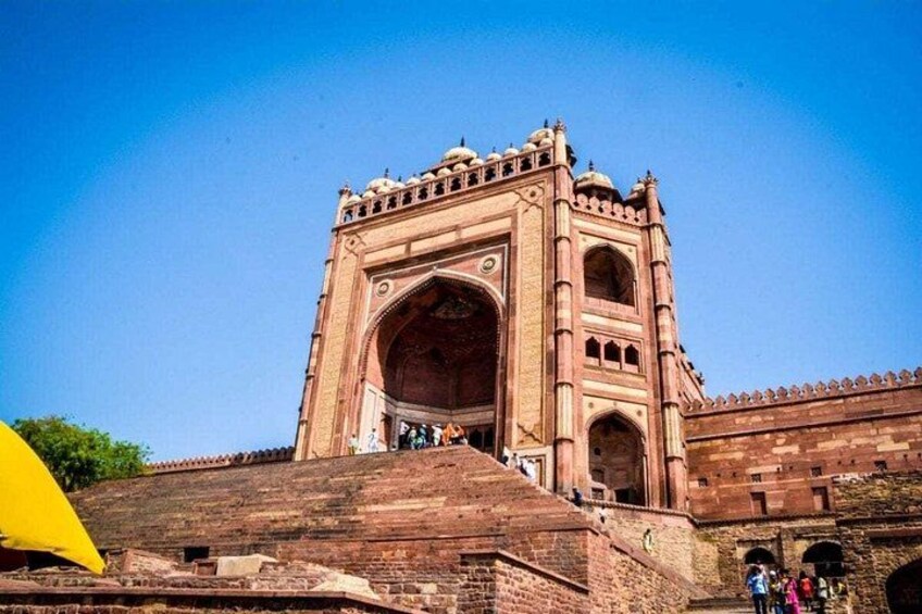 A large, historic red-brick structure with multiple arches and a central dome, likely a significant architectural landmark. 1