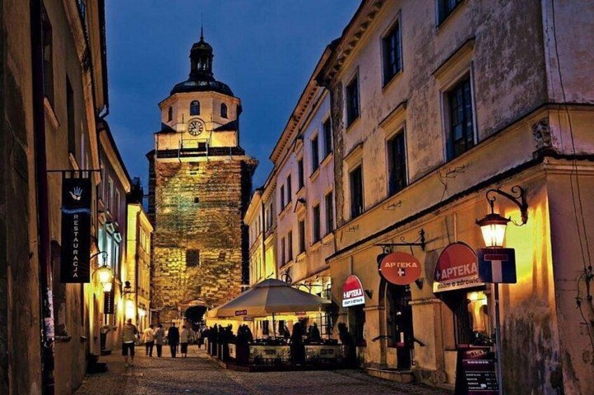A historic tower, a street with shops, and a café with outdoor seating. 4