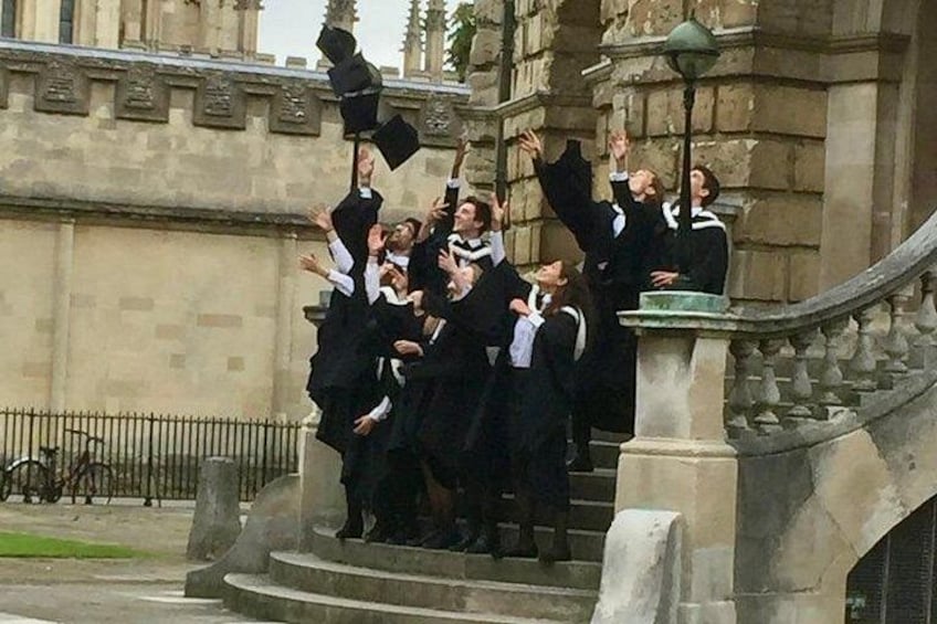 A group of people in academic regalia celebrating on a staircase. 5