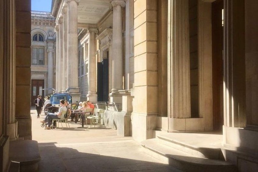 Une rue bordée de bâtiments à l’architecture classique, avec des colonnes et des escaliers. 2