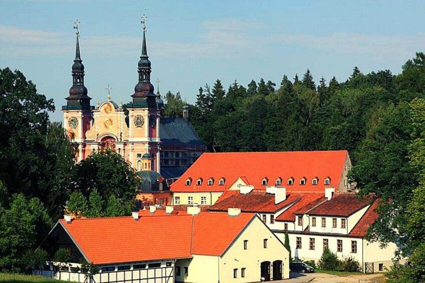 A church with two towers, a red-roofed building, and surrounding greenery. 2