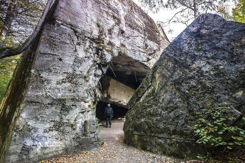 A person walking through a natural rock formation with a cave-like entrance. 1