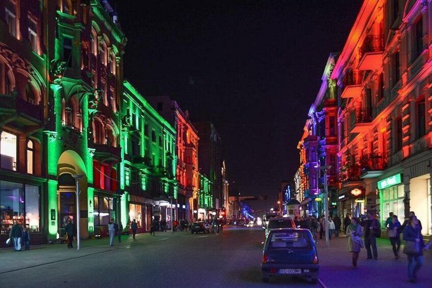Una calle iluminada con luces de noche, edificios coloridos y un automóvil en primer plano. 5