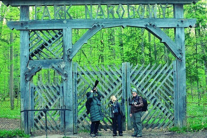 Una verja de madera en un área boscosa, con personas paradas frente a ella. 5