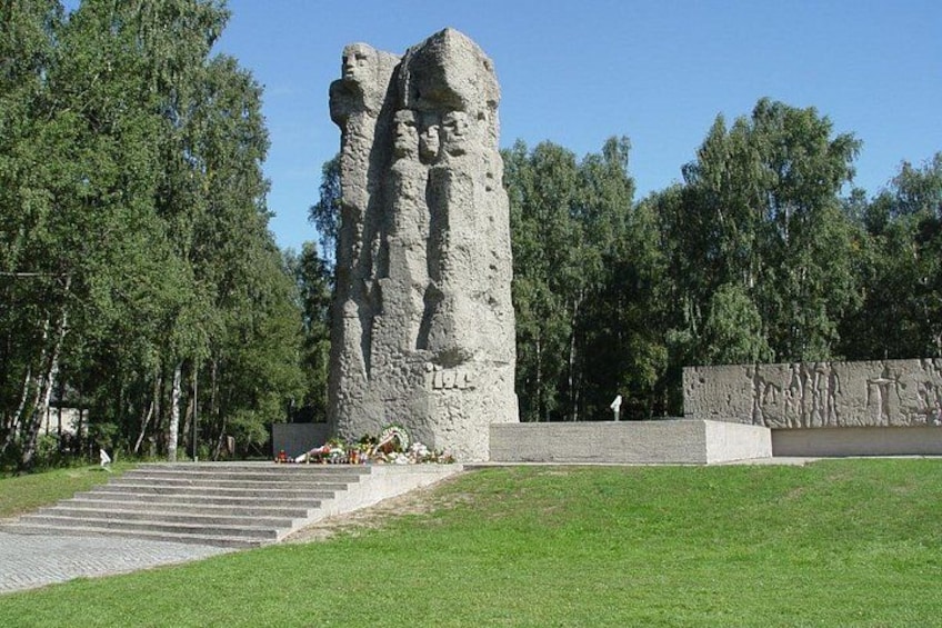 A large stone monument with steps leading up to it, surrounded by trees and a grassy area. 5