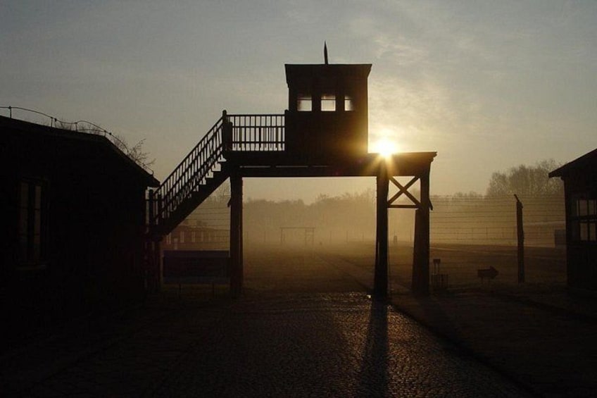 A wooden structure with a staircase, a watchtower, and a fence in a rural setting. 1