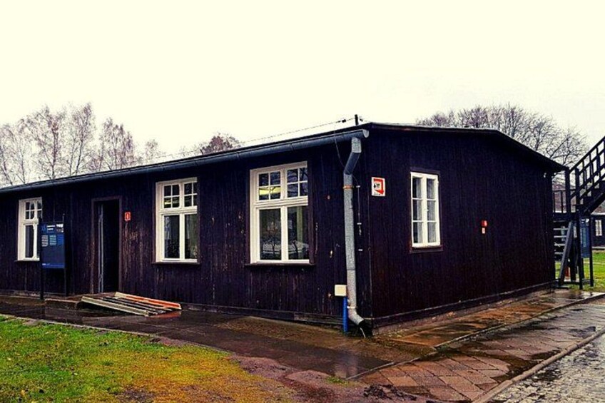 A black building with white windows and a door, a blue sign, and a metal staircase. 3