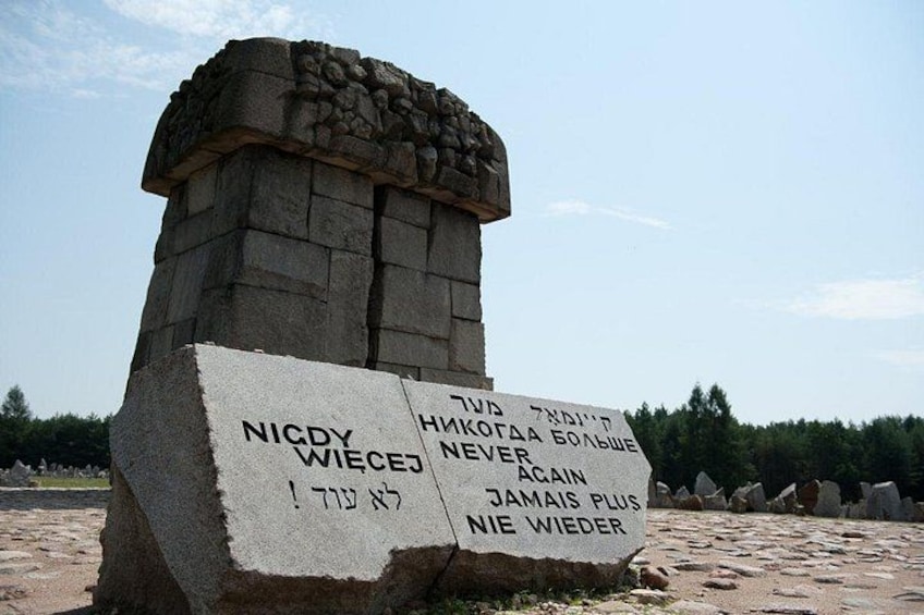 A stone monument with inscriptions in multiple languages, surrounded by a natural landscape. 5