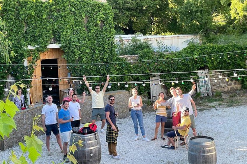 A group of people outdoors with a wooden structure, string lights, and barrels. 4