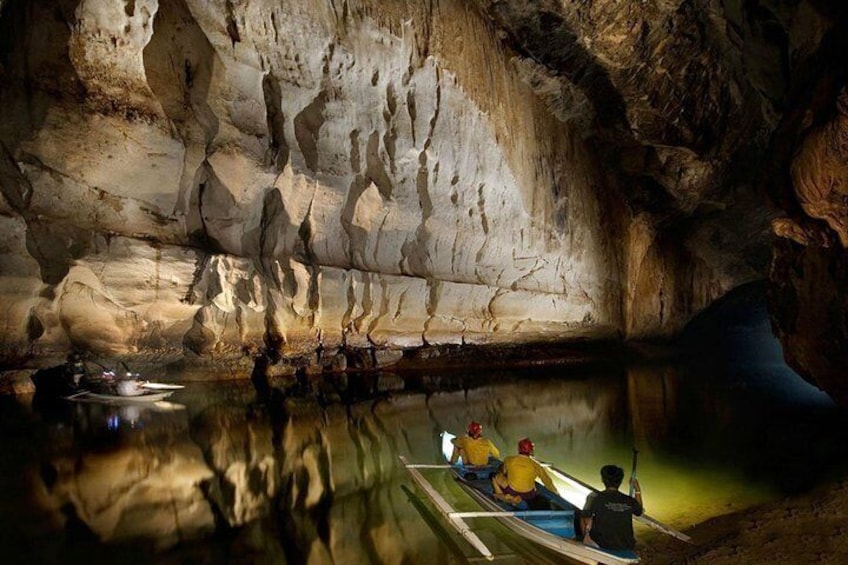 Een grot met stalactieten en stalagmieten, en mensen die kanoën. 1
