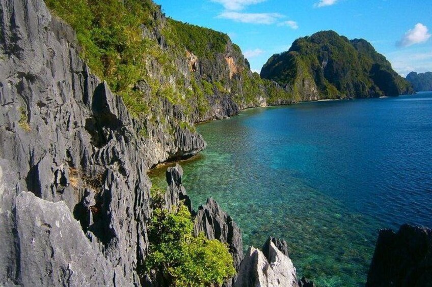 A coastal landscape with rocky cliffs and clear blue waters. 3