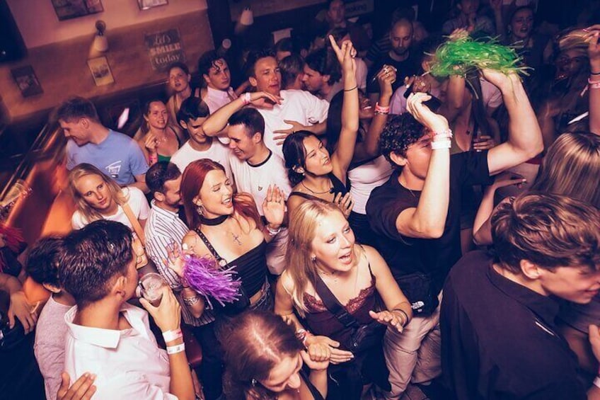 Een druk binnen evenement, mensen dansen en houden groene voorwerpen omhoog. 5