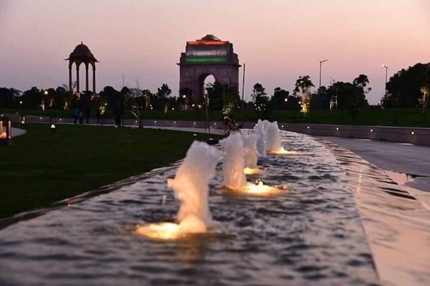 Une fontaine avec de nombreux jets d’eau, un grand monument en forme d’arche et un kiosque en arrière-plan. 1