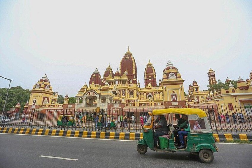 Un tuk-tuk vert sur une route, avec un grand temple richement décoré en arrière-plan. 2