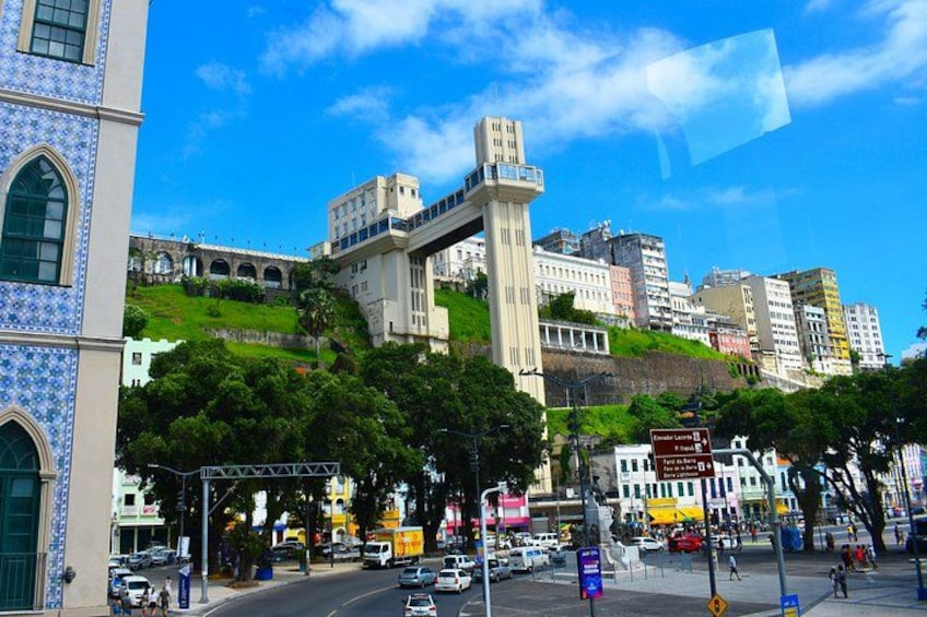 A cityscape with a prominent tower, a cathedral with blue tiles, and a busy street with vehicles and pedestrians. 3