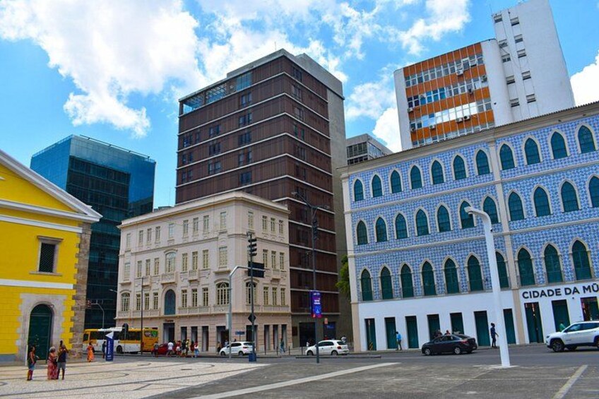A city street with modern and historic buildings, a bus, and pedestrians. 4