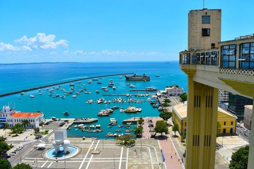A coastal city with a marina, buildings, and a prominent tower. 5